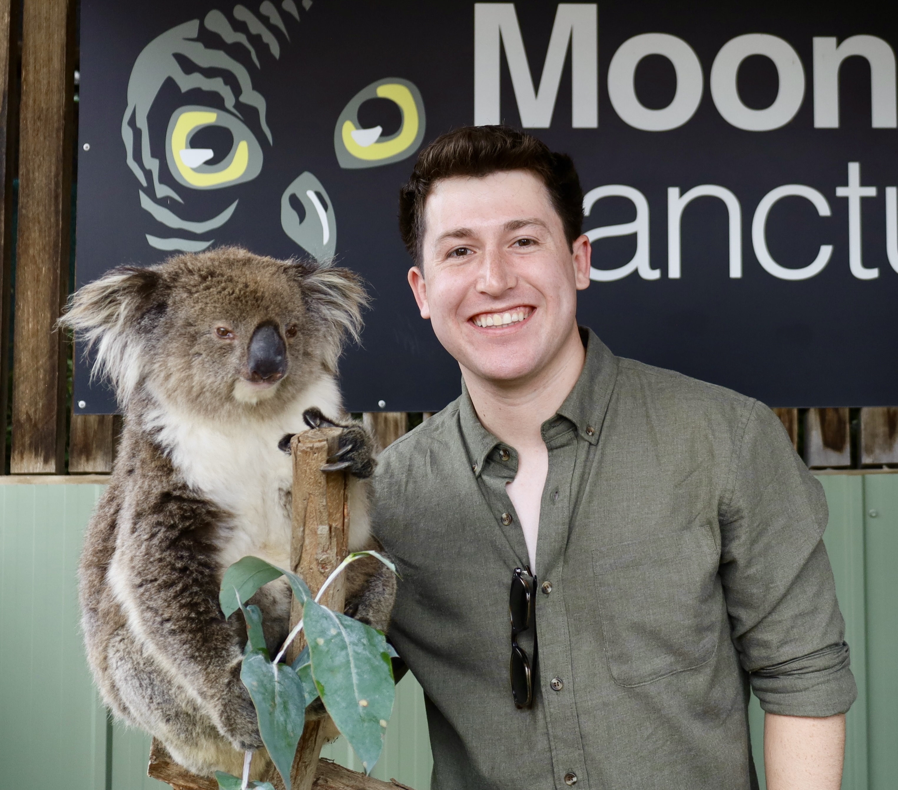 Michael is standing next to a koala bear and smiling at the camera.